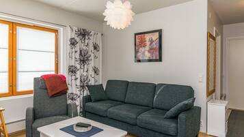 A modern living room with a grey sofa, a white coffee table, and a hanging light fixture.
