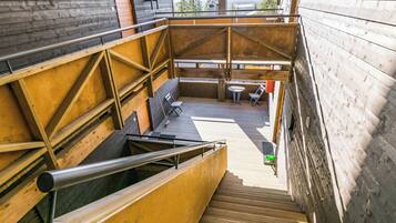 A wooden staircase leading to a deck with outdoor seating and a view of the surrounding landscape.