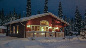 Una cabaña con terraza de madera y un paisaje cubierto de nieve.