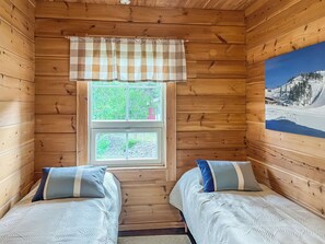 A cabin room with two beds, a window with a view of greenery, and a painting on the wall. - Heikkalan helmi by Interhome (Kuusamo)