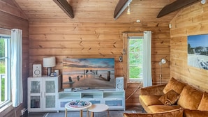 Una sala de estar acogedora con detalles de madera, un televisor de pantalla plana grande, un sofá cómodo y una mesita de centro pequeña.