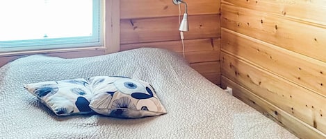 A room with a bed, a window with blinds, a lamp, and a curtain with a floral pattern.