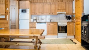 A kitchen with wooden cabinets, a refrigerator, a microwave, a coffee maker, a dishwasher, an oven, and a washing machine.
