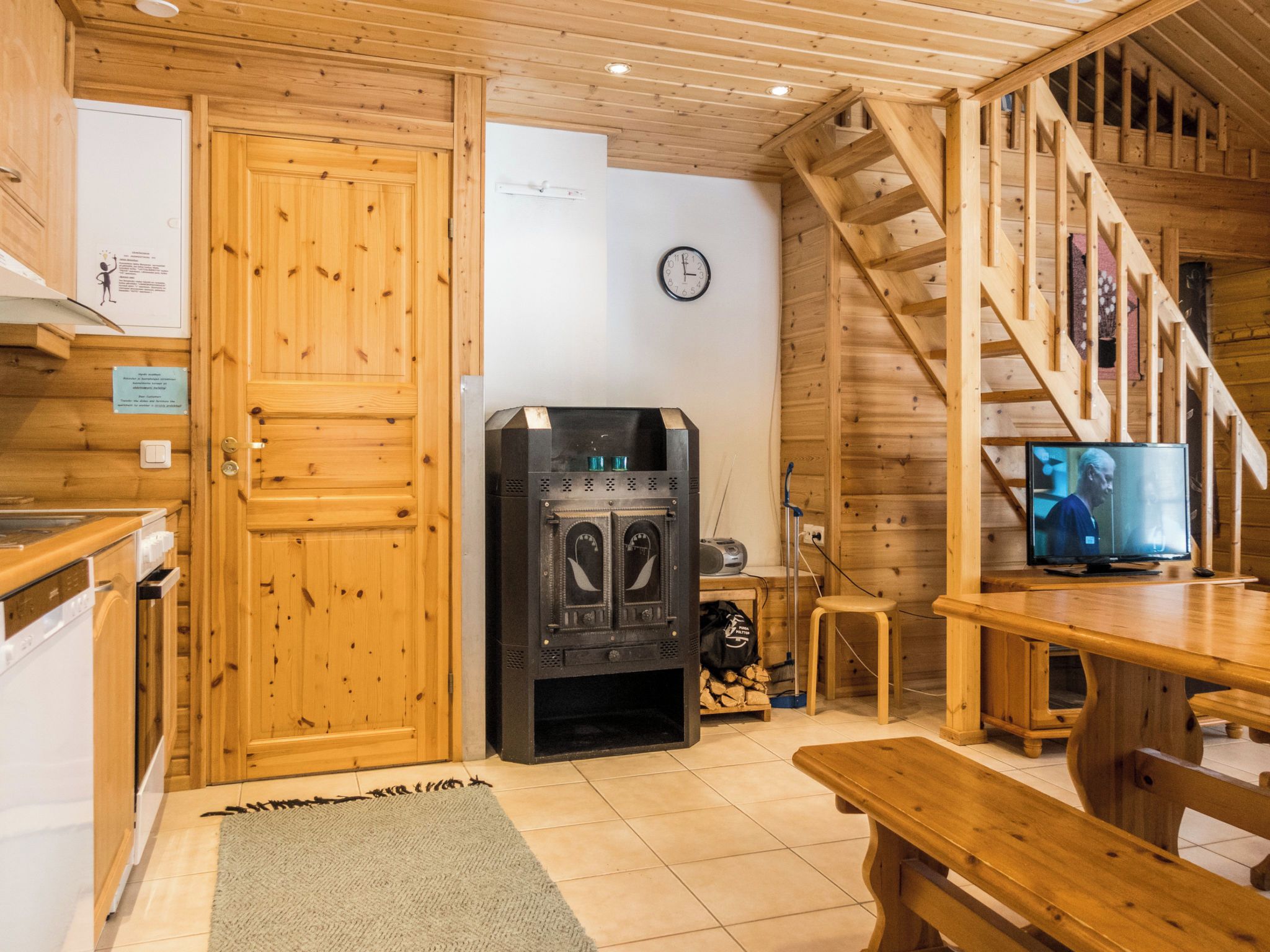 A wooden interior with a kitchen, a fireplace, a dining area, and a staircase.