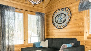A cozy living room with a dark grey sofa, a white coffee table, and a decorative circular wall hanging.