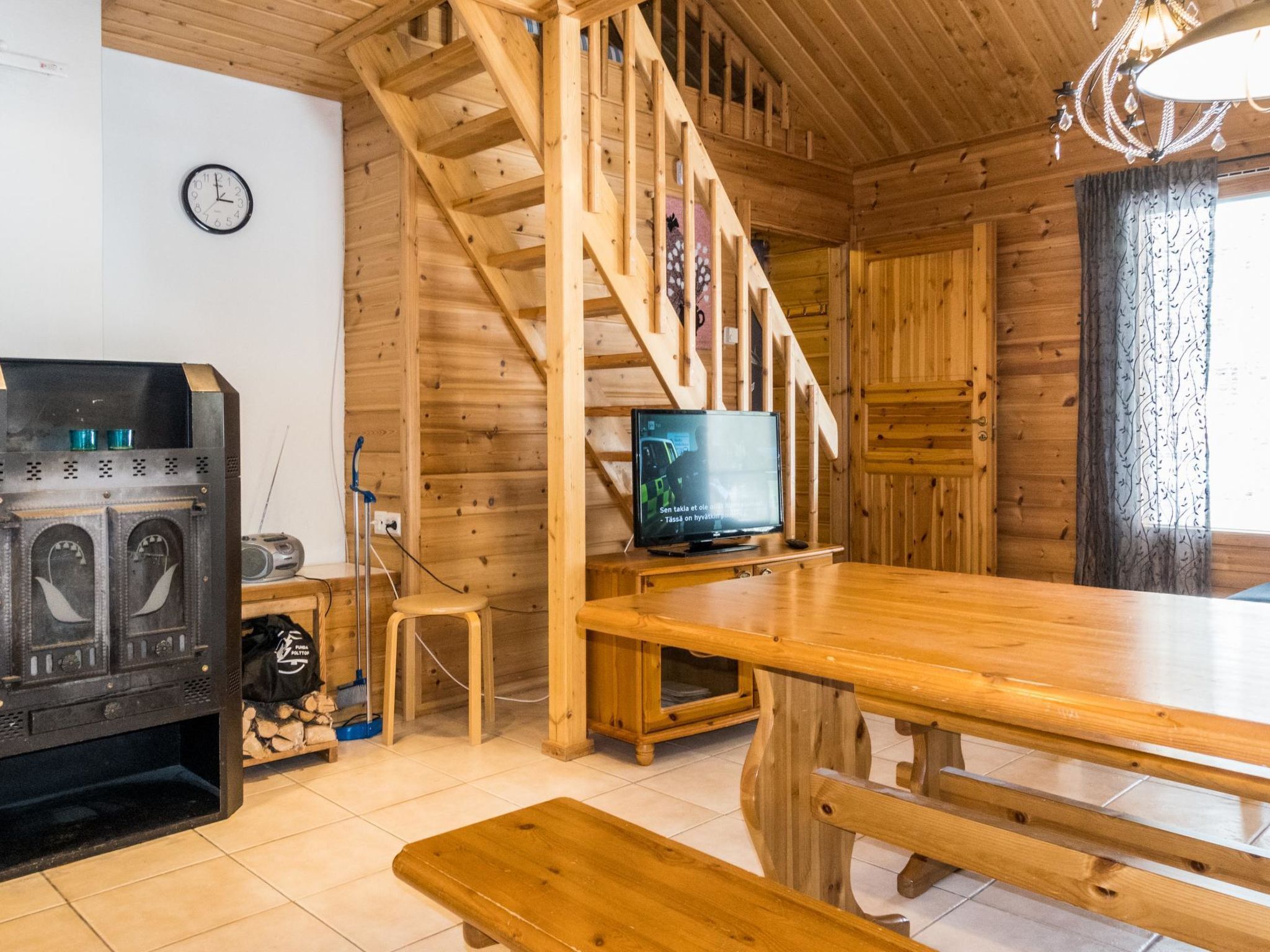 Ein Holzinnenraum mit Treppe, Fernseher, Kamin und einer Wanduhr.