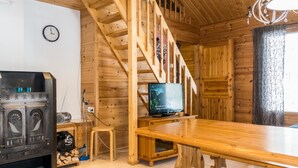A wooden interior with a staircase, a television, a fireplace, and a clock on the wall.
