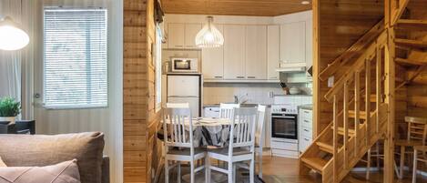 Une cuisine moderne avec des meubles en bois, une table à manger avec des chaises et un escalier menant à l’étage supérieur.