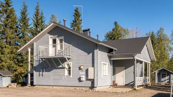 A two-story house with a balcony, a garage, and a small shed.