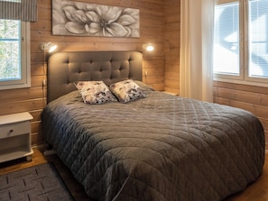 A bedroom with a tufted headboard, a large floral artwork above the bed, and two bedside lamps.