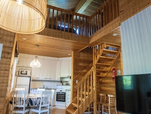 Un interior de madera con cocina, comedor y una escalera que conduce a un nivel superior.