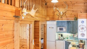A wooden interior with a kitchen area, including a refrigerator, microwave, and cabinets. - Hamppulahti by Interhome (Kuhmo)