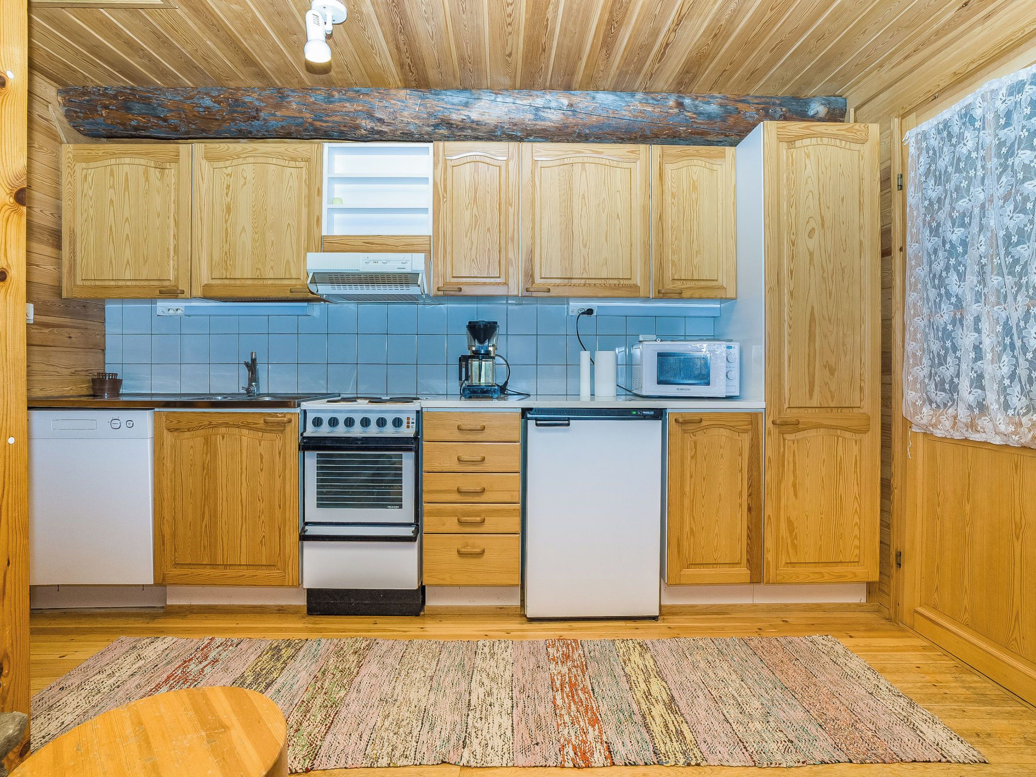 A compact kitchen with wooden cabinets, a stove, a microwave, and a coffee maker.