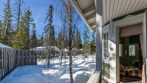 A wooden deck with a view of a snowy landscape and trees.