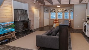 A cozy living room with a stone fireplace, a large flat-screen TV, and a comfortable sofa.