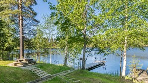 Un espace de pique-nique au bord du lac, avec une terrasse en bois, une table de pique-nique et des marches menant à l’eau.