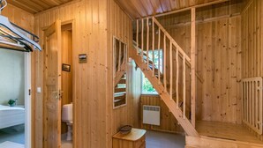 L’intérieur d’un chalet en bois comprend un escalier, une petite salle de bain et un banc en bois.