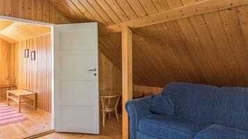 Un intérieur en bois avec un canapé bleu, une porte donnant sur une autre pièce et une petite table.