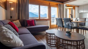 A modern living room with a sofa, two round tables, and a dining area with chairs. - Zurschmitten 17 1. OG Süd by Interhome (Riederalp)