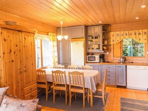 Ett mysigt kök i stugstil med träskåp, ett matbord och en inbyggd mikrovågsugn.