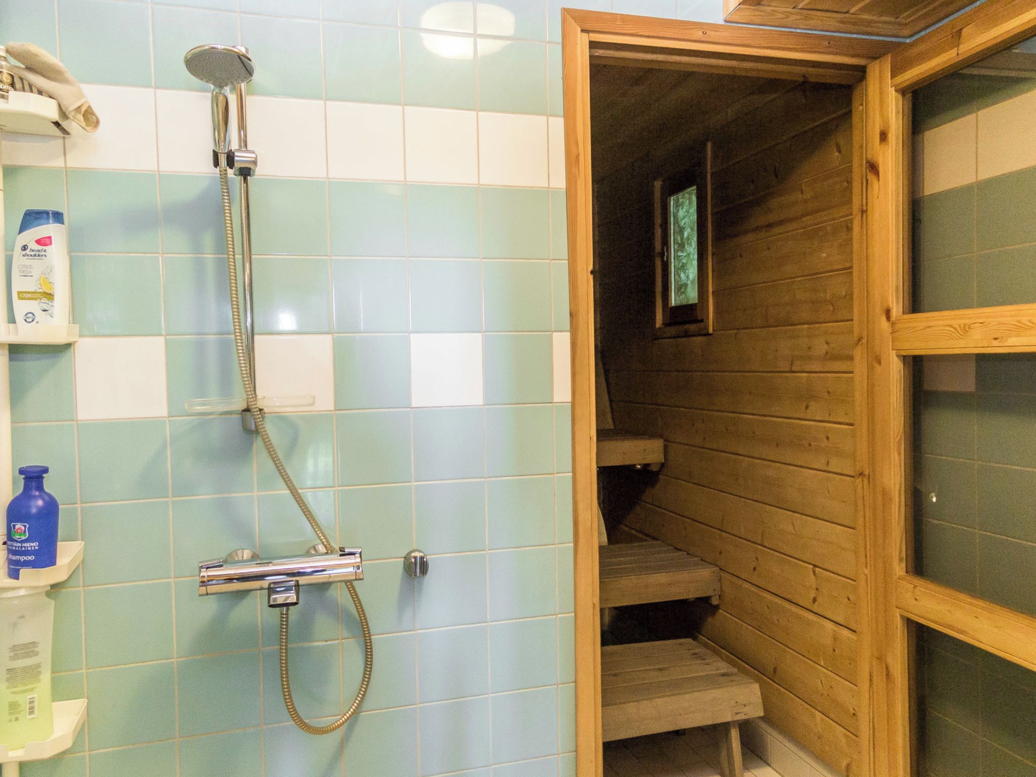 A bathroom with a shower, a wooden bench, and a window.