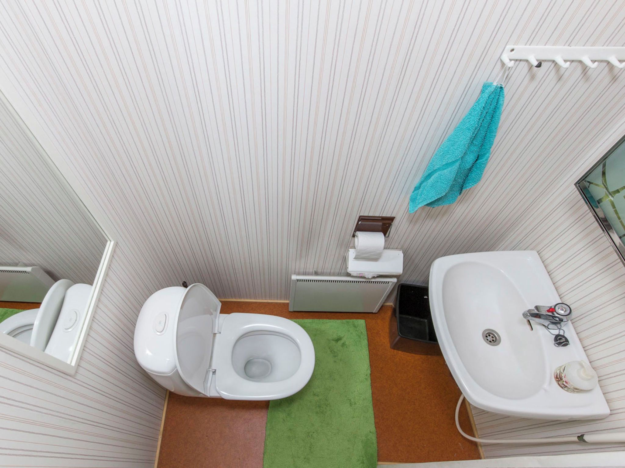 Casa de banho pequena com sanita, lavatório e suporte para toalhas.