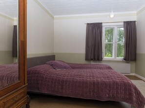 Une chambre avec deux lits, une fenêtre avec des rideaux et un miroir.