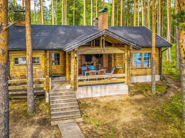 A cabin with a porch, outdoor seating, and a chimney.