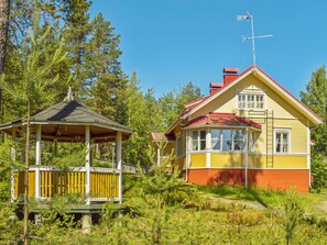 A two-story house with a red roof and a wooden deck.