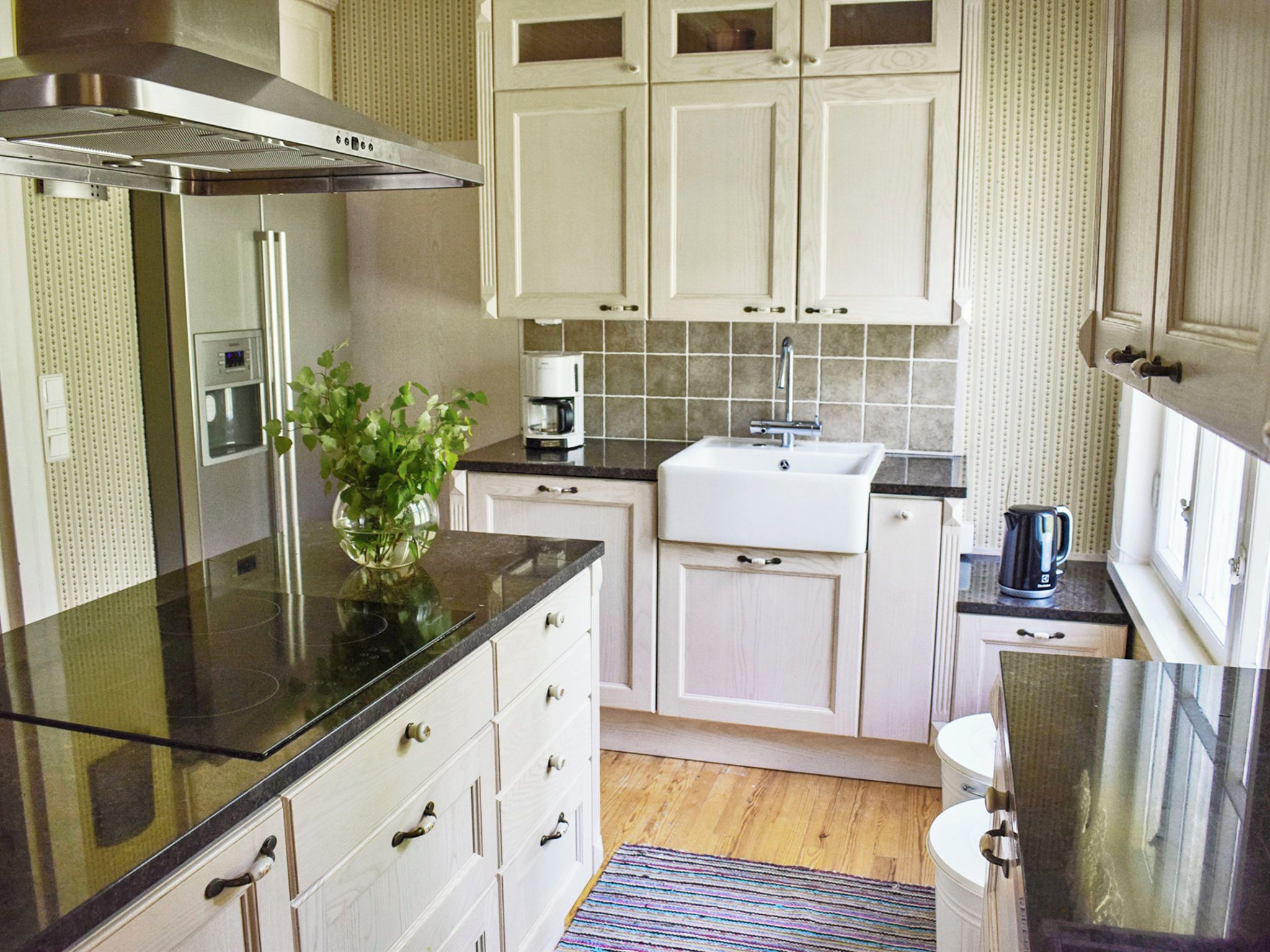 A modern kitchen with stainless steel appliances, white cabinetry, and a coffee maker.