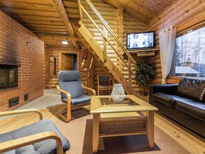 A log cabin interior with a fireplace, a television, a staircase, and a sofa. - Heporanta by Interhome (Hankasalmi)