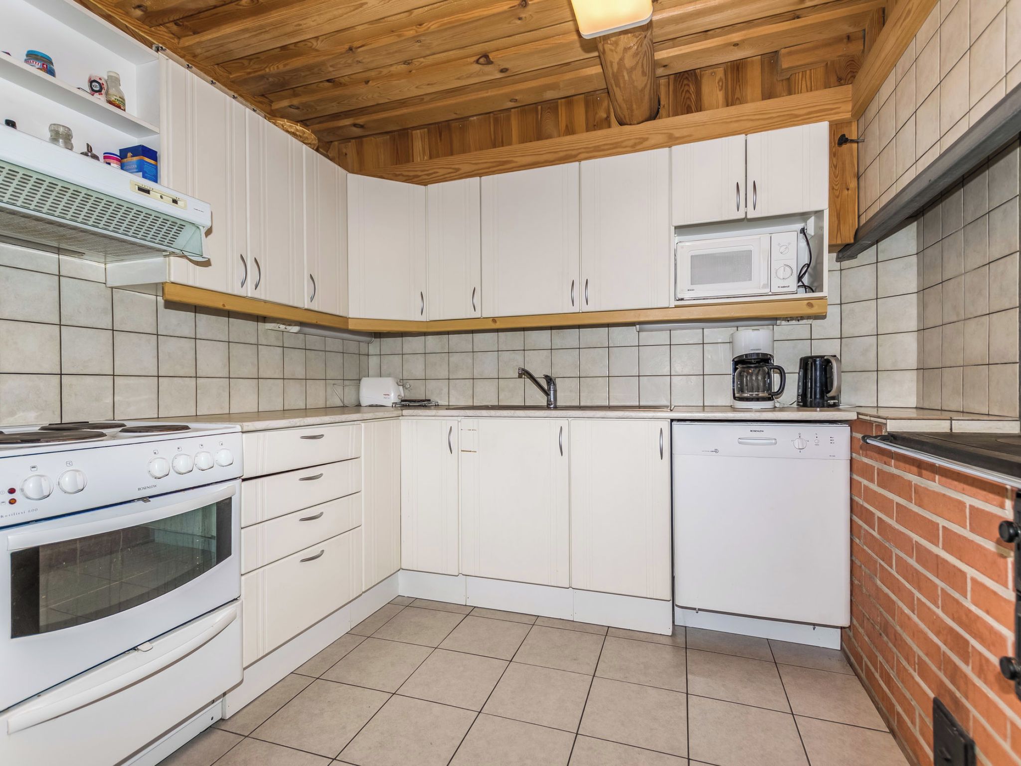 Een keuken met witte kastjes, een magnetron, een koffiezetapparaat en een vaatwasser.