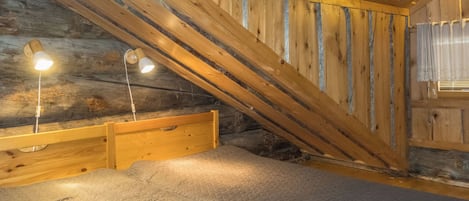 Een kamer met een schuine balkenplafond en een bed met hoofdeinde.