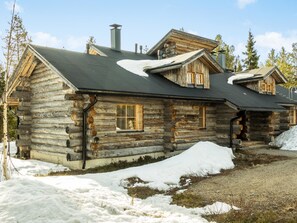 A log cabin with a steeply pitched roof, a chimney, and a small porch.