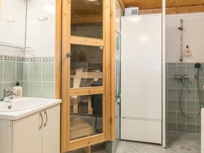 A bathroom with a wooden cabinet, a white sink, a glass-enclosed shower area, and a white toilet.
