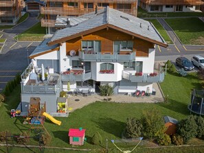 A multi-story building with balconies, a children's play area, and a small red-roofed structure.