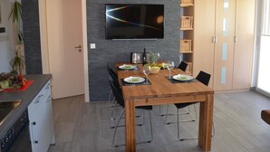 Un comedor moderno con una mesa de madera, sillas y un televisor de pantalla plana montado en la pared.
