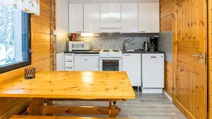 A compact kitchen with white cabinets, a microwave, a stove, and a coffee maker. - Lepikko by Interhome (Kaavi)