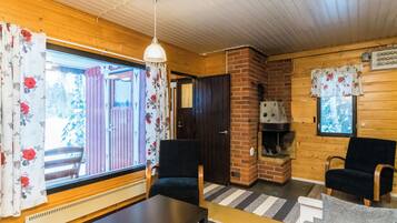 Ein gemütliches Blockhaus-Interieur mit Kamin, Holzwänden und einem großen Fenster mit Vorhängen.