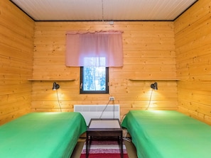 Habitación pequeña y acogedora con dos camas individuales, un calentador y ventana con vista a árboles.