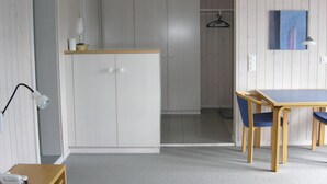A room with a wooden table and chairs, a white wardrobe, and a hanging coat rack.