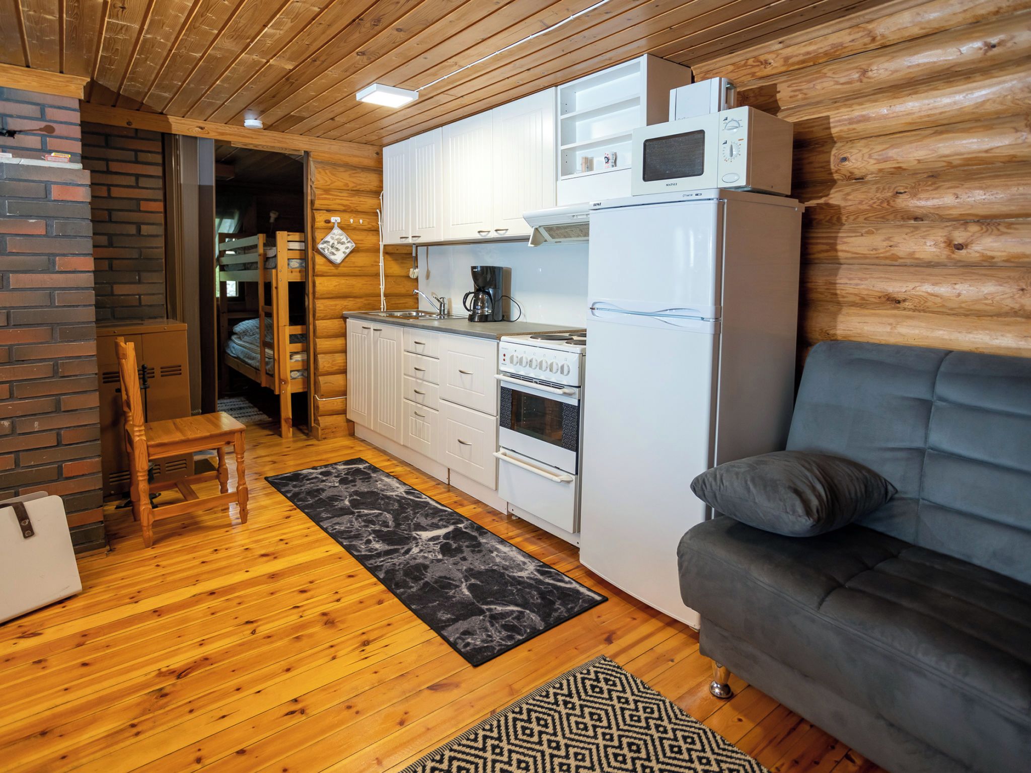 Un espacio habitable compacto con kitchenette, un sofá, una cafetera y un microondas.