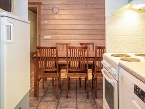 A kitchen with wooden chairs, a dining table, a stove, and a microwave.