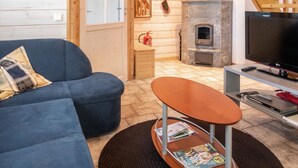 A cozy living room with a blue sofa, a small wooden table, a fireplace, and a TV.