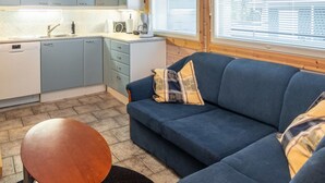 A compact living space with a kitchenette, a sofa, and a round table.