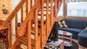 A wooden staircase leading to a living area with a sofa and a television.