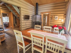 A log cabin interior with a dining table, chairs, a fireplace, and a staircase. - Ylläsmaisema 1 by Interhome (Ylläsjärvi)