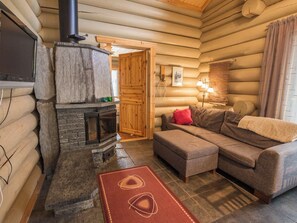 A log cabin interior with a stone fireplace, a sofa, and a television. - Ylläsmaisema 1 by Interhome (Ylläsjärvi)