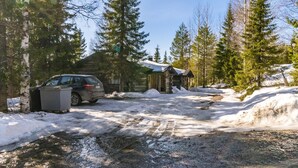 A cabin with a wooden exterior, a car parked in front, and a snow-covered ground.