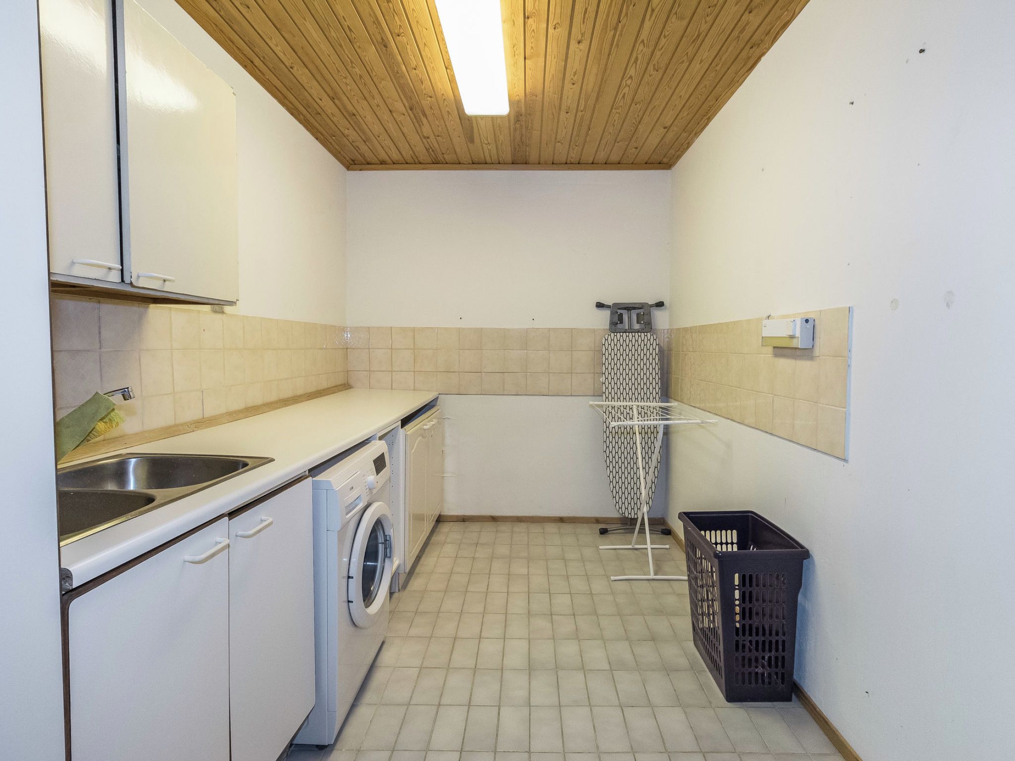 Un espai petitú per a la bugateria amb una rentadora, un lavabo i un tendal.